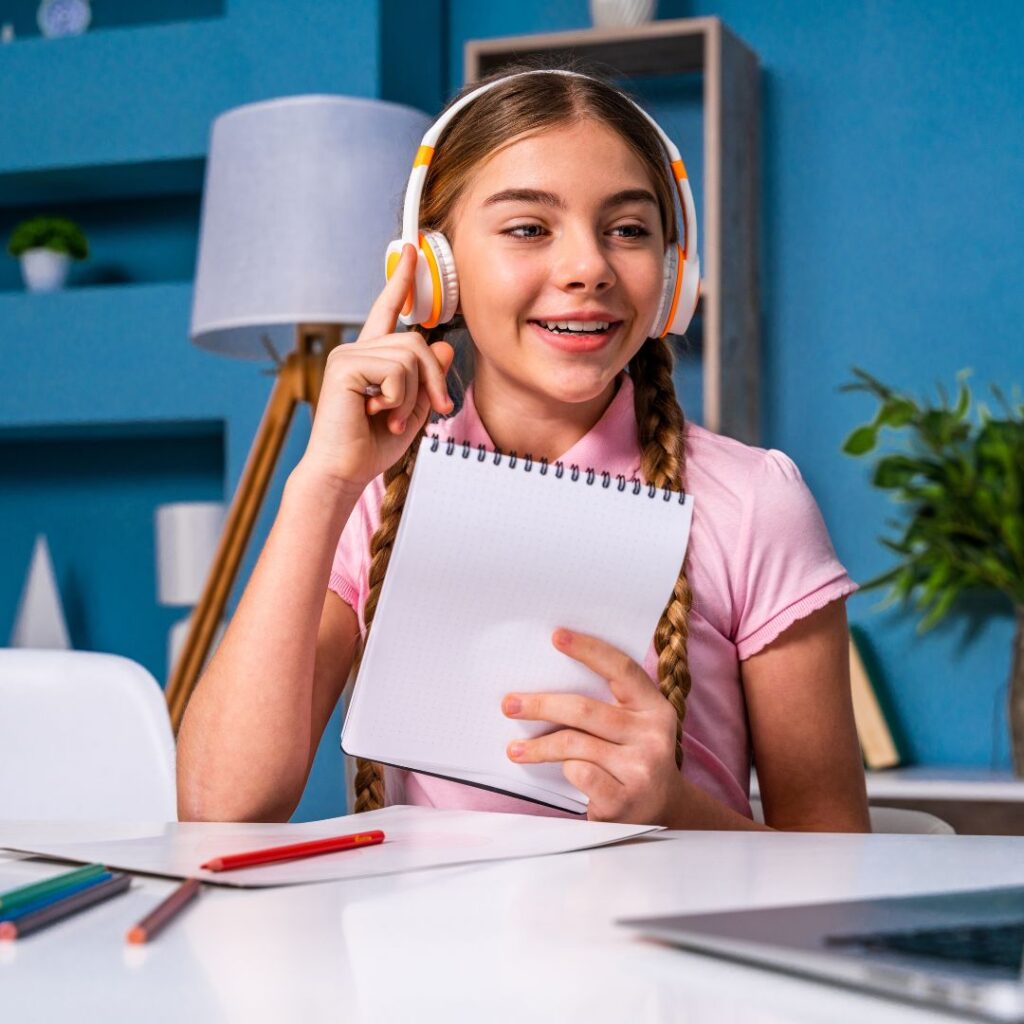 preteen girl working on computer with notebook