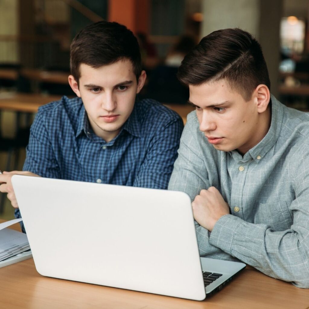 two boys look at a computer