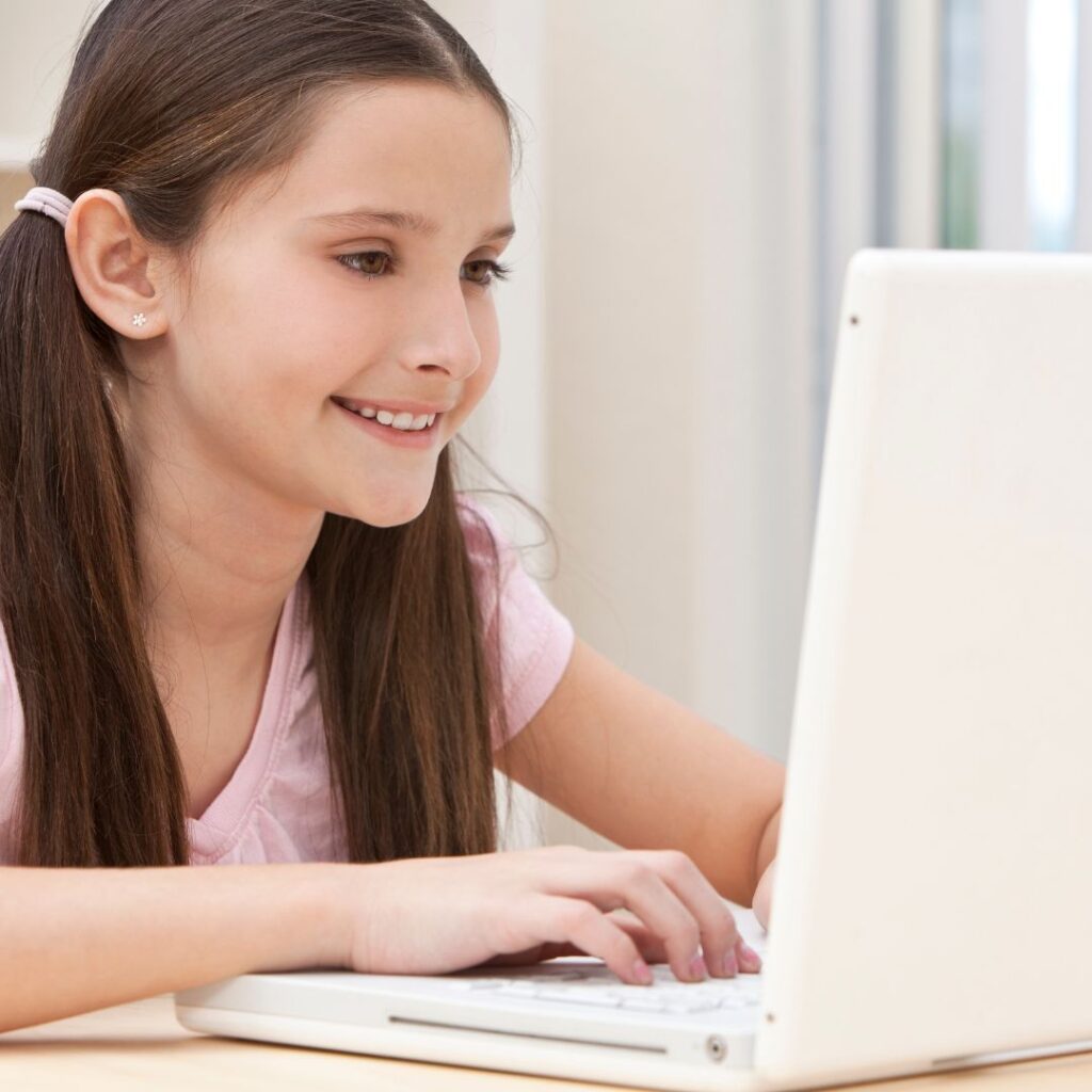 girl smiling as she is using her computer