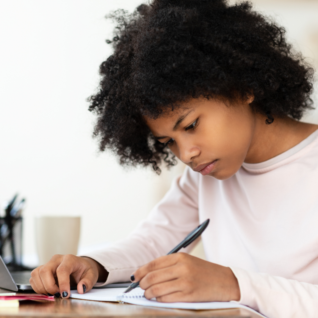 a child writing with pen in a notebook